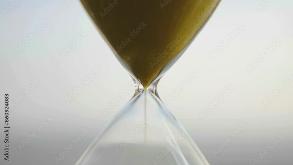 hourglass on table, close up sand flowing through the bulb of sandglass, time is money concept, times passing concept like work or business deadline, resemble urgency running out of occasion in life
