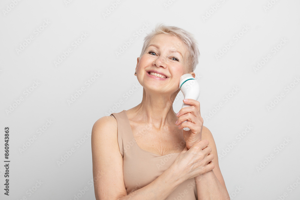 Beautiful 60s woman holding a massager in her hand. Spa technique skincare ads. Beautiful 60s woman holding a massager in her hand. Spa technique skincare ads.