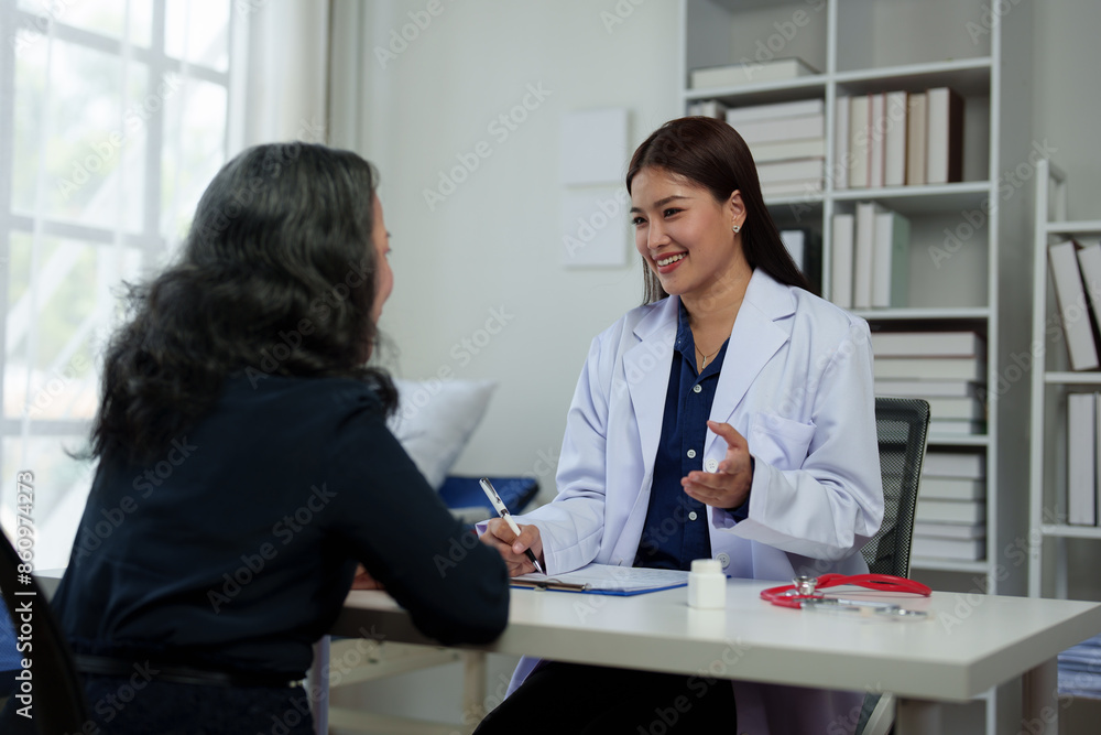 Confident Asian female doctor explains and questions a retired female patient attending a private clinic for treatment and therapy. Health concept, health insurance. Confident Asian female doctor explains and questions a retired female patient attending a private clinic for treatment and therapy. Health concept, health insurance.