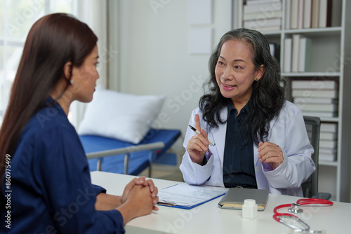 Asian elderly doctor explaining Advising Asian female patients about medicines in hospital Asking about illness history Health check and encouragement health insurance concept.