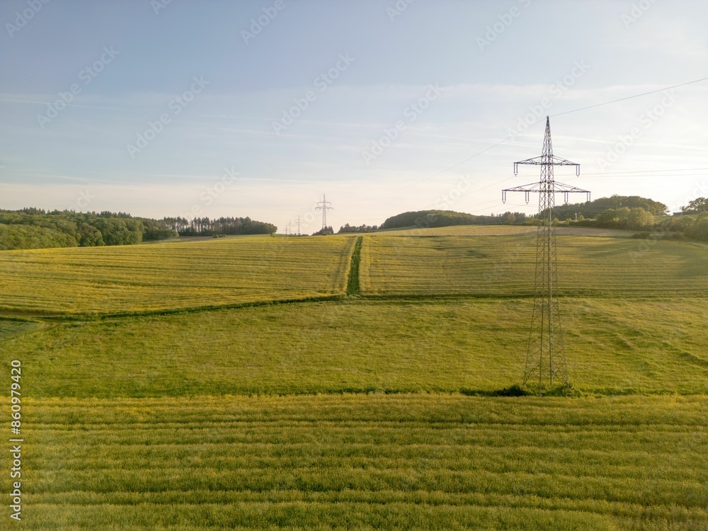 Scenic view of a green field with power lines and a clear sky in the background Scenic view of a green field with power lines and a clear sky in the background