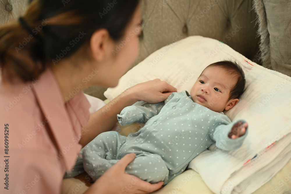 Cute newborn baby lying on soft sofa with mother. Motherhood and child care concept Cute newborn baby lying on soft sofa with mother. Motherhood and child care concept