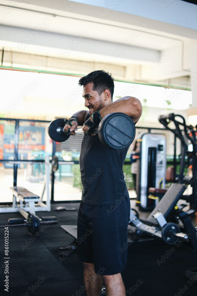 Young Asian Muscular Man Working Out In Gym Doing Exercises With Barbell At Biceps. Young Asian Muscular Man Working Out In Gym Doing Exercises With Barbell At Biceps.