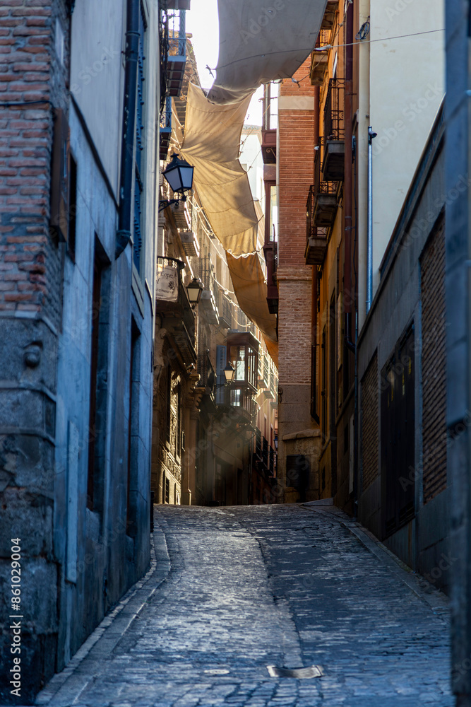 Fototapeta premium Narrow street in Toledo with awnings in the early morning. Castile la Mancha, Spain.