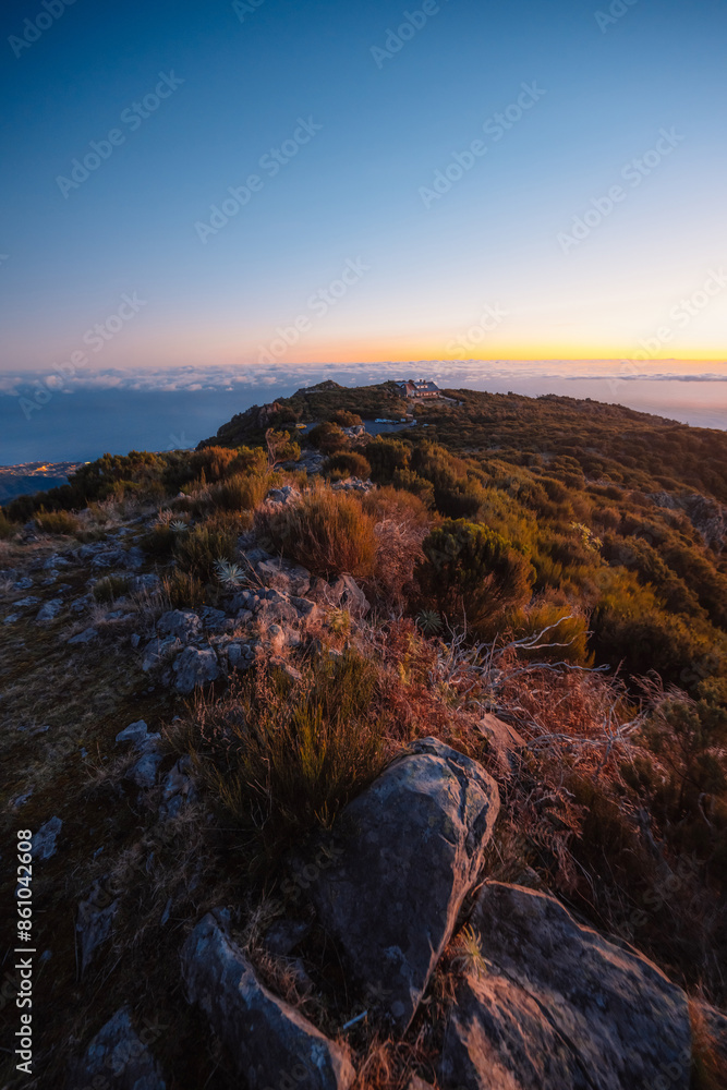 Naklejka premium Hiking on the highest peak of Madeira Pico Ruivo next to the cottage Abrigo do Pico Ruivo. Views of the surrounding mountains lanscape during sunrise