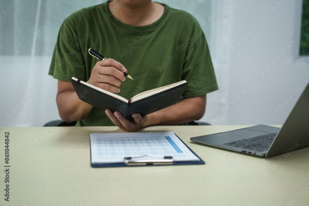 A householder manages household expenses while working at a desk, tracking various costs such as transportation, housing, groceries, dining, healthcare, utilities, and personal items to maintain A householder manages household expenses while working at a desk, tracking various costs such as transportation, housing, groceries, dining, healthcare, utilities, and personal items to maintain