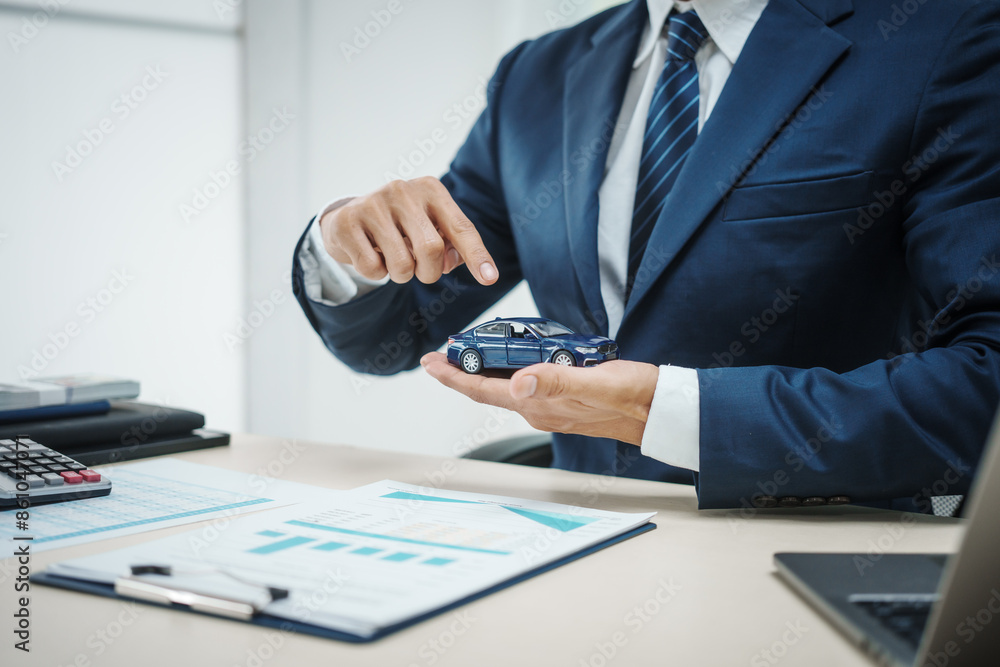 A man in a suit works at his desk selling cars and online car insurance with low interest rates, offering car loans, vehicle financing, and comprehensive vehicle coverage A man in a suit works at his desk selling cars and online car insurance with low interest rates, offering car loans, vehicle financing, and comprehensive vehicle coverage