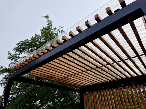 modern market stand made of metal pergola structure with slats on the sides of the walls. the striped appearance of the smoking shelters at the bus stop photo