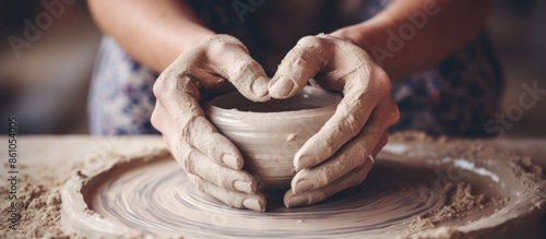 A top view image of a woman's white hands shaping pottery on a horizontal pottery wheel, with a focus on the hands and no face, ideal for copy space in the image. photo