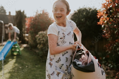 Fotografia Girl with Down Syndrome doing laundry, house chore