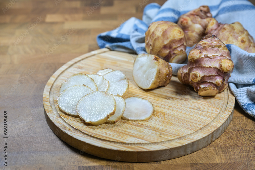 Tubers of Jerusalem artichoke or topinambur (Helianthus tuberosus), whole and slices on a kitchen board, healthy root vegetable with inulin recommended for diabetes diet, copy space Tubers of Jerusalem artichoke or topinambur (Helianthus tuberosus), whole and slices on a kitchen board, healthy root vegetable with inulin recommended for diabetes diet, copy space