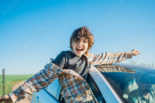 Happy boy leaning out of car window on sunny day photo