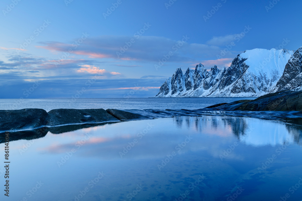 Iceberg near Norwegian sea and Okshornan mountains at sunset in Senja island, Troms, Norway