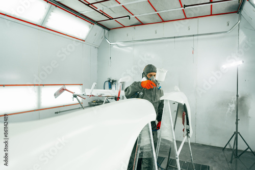 Canvas Print Auto painter painting a car with vaporizer gun inside a paint booth
