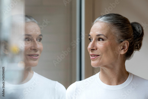 Wallpaper Mural Smiling senior gray haired woman looking out through window Torontodigital.ca