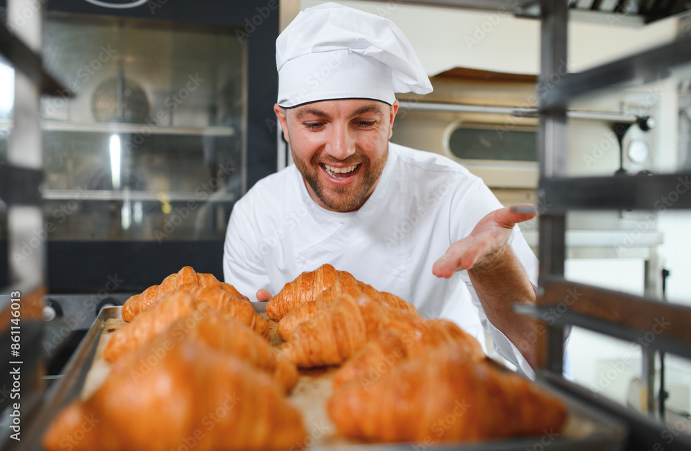 Smiling baker holding tray with fresh cooked croissants in bakehouse Smiling baker holding tray with fresh cooked croissants in bakehouse