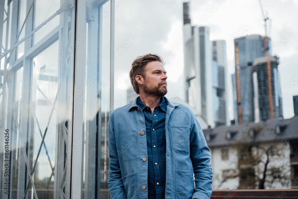 Contemplative mature man leaning on metal pillar