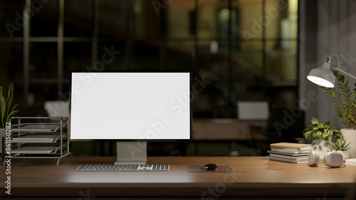 A contemporary office at night features a PC computer mockup and a dim light from a table lamp.