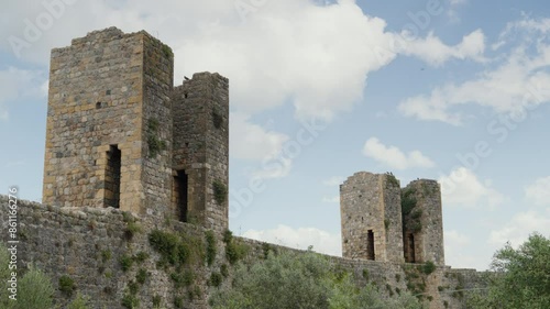 Ancient stone towers amid Tuscan landscape under blue sky. photo