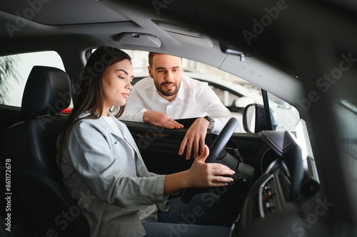 friendly vehicle dealer showing young woman new car