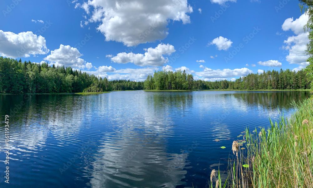 Summer wilderness lake and forest landscape with blue water and sky with white clouds Finland Summer wilderness lake and forest landscape with blue water and sky with white clouds Finland
