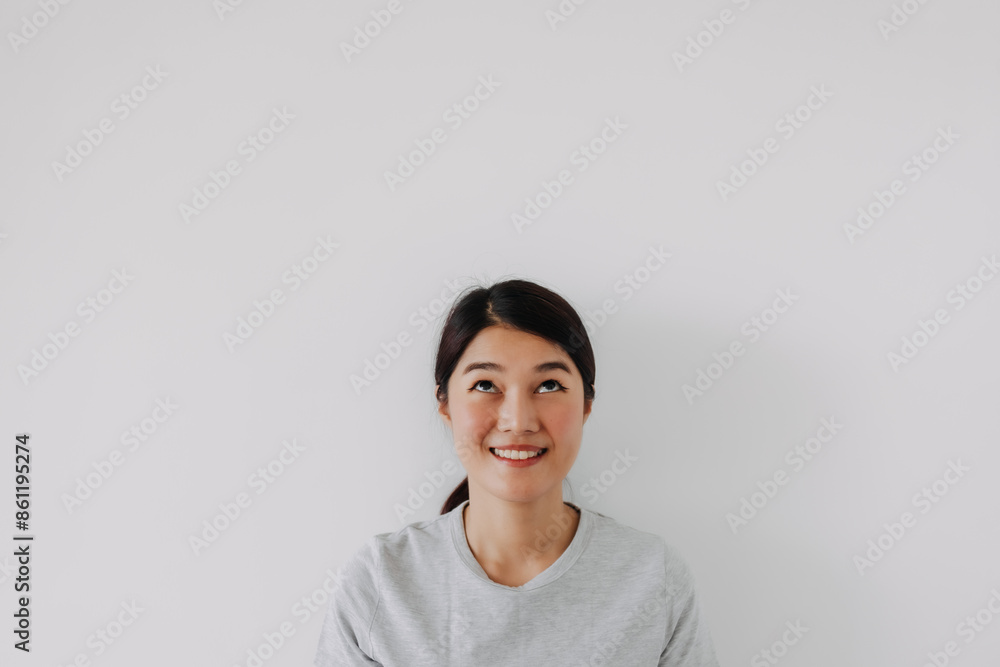 Happy asian woman smiling look at empty space above, isolated over white background wall. Happy asian woman smiling look at empty space above, isolated over white background wall.