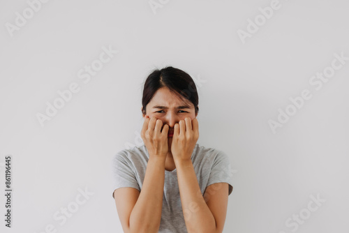 Asian Thai woman crying funny face, sad and disappointed, hands cover face standing isolated over white background wall.
