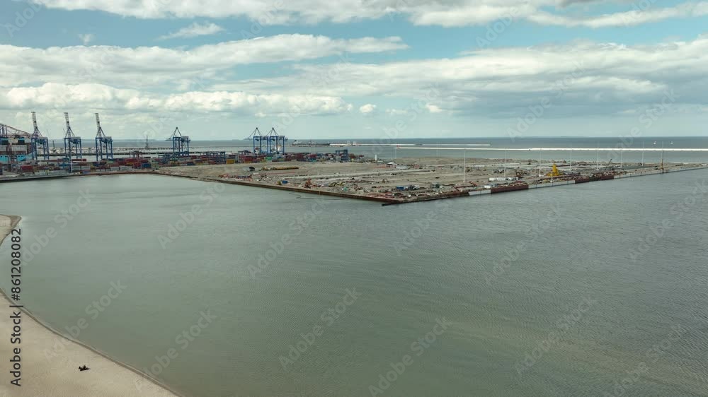 Aerial view of the new HUB terminal at Gdansk Stogi harbor with cranes and containers under a cloudy sky -the process of building a new transshipment terminal Aerial view of the new HUB terminal at Gdansk Stogi harbor with cranes and containers under a cloudy sky -the process of building a new transshipment terminal