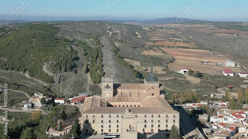 reverse flight visualizing the impressive monastery of Ucles founded in the 12th century and expanded in the 16th-17th century, its wonderful surroundings and the town of Ucles appear photo