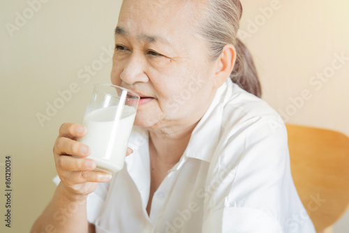 Obraz na plátně Asian senior mature aged woman drinking milk for calcium food and healthy