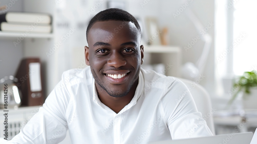 Professional black man, sitting at a desk in minimal white office, relaxed expression, close-up portrait. Professional black man, sitting at a desk in minimal white office, relaxed expression, close-up portrait.