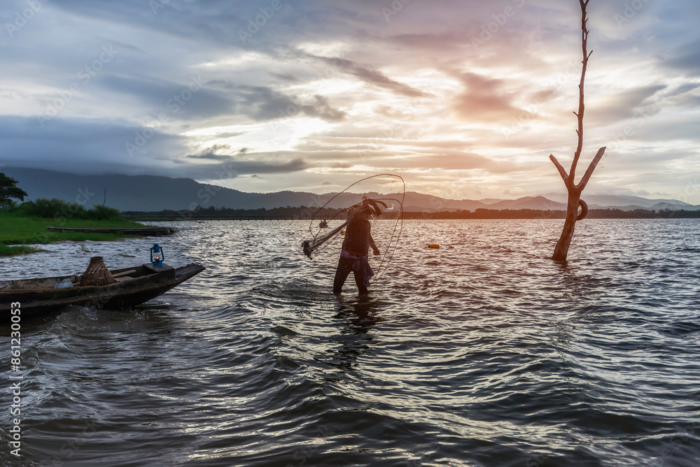 Fototapeta premium Asian fisherman on wooden boat casting a net for catching freshwater fish in nature river in the early morning before sunrise