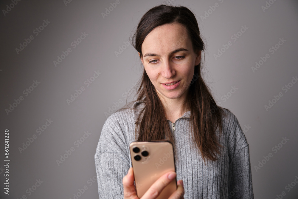 portrait of a young woman, teen model with a happy expression, looking at a smartphone and standing in front portrait of a young woman, teen model with a happy expression, looking at a smartphone and standing in front