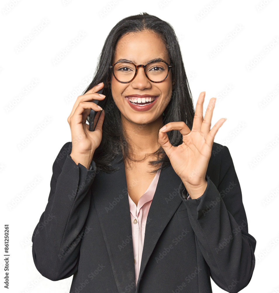 Latina in suit with phone in studio cheerful and confident showing ok gesture. Latina in suit with phone in studio cheerful and confident showing ok gesture.