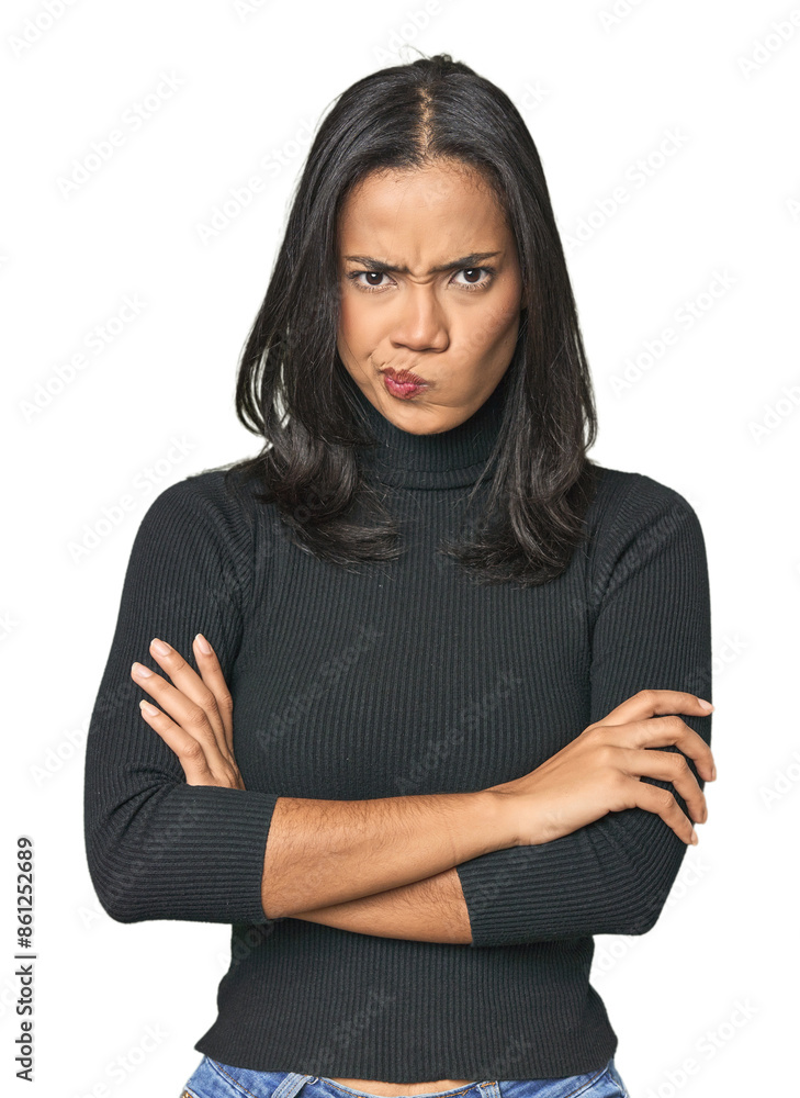 Simple portrait of a young Latina frowning face in displeasure, keeps arms folded. Simple portrait of a young Latina frowning face in displeasure, keeps arms folded.