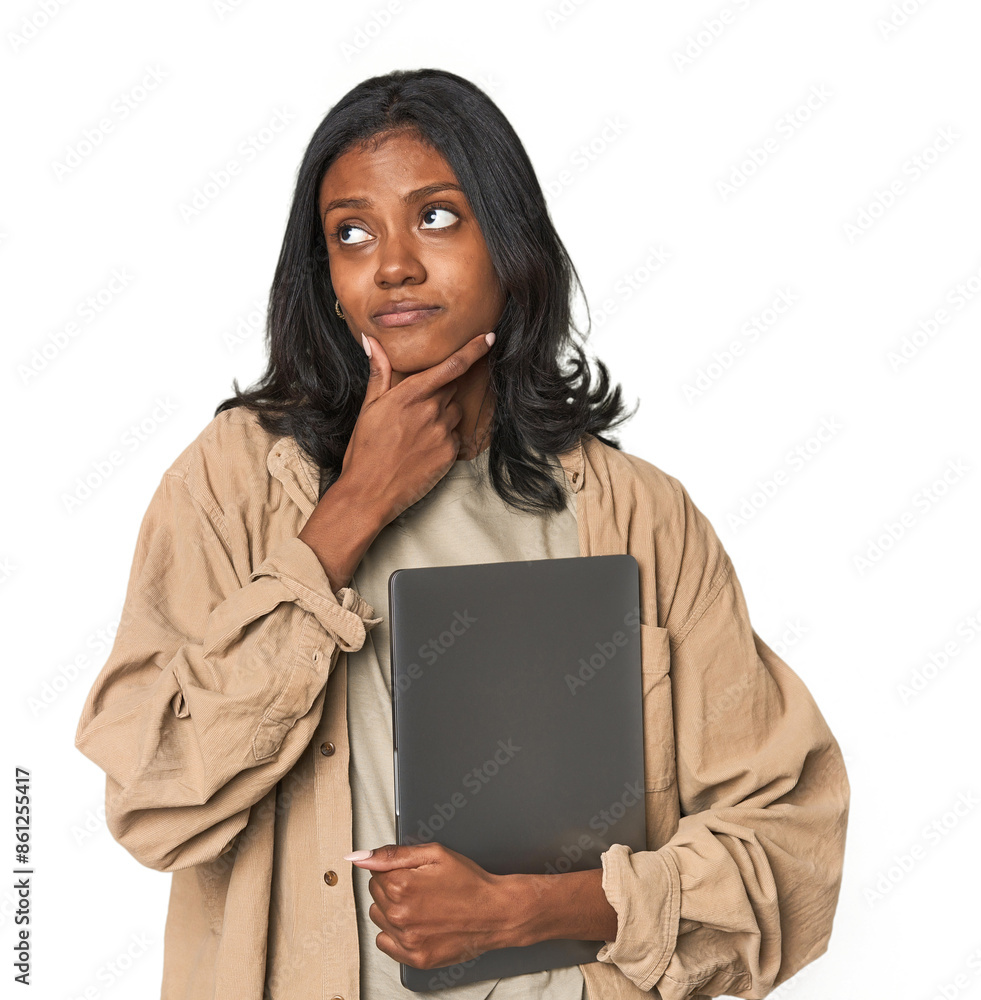 Fototapeta premium Young Indian woman studying with laptop looking sideways with doubtful and skeptical expression.
