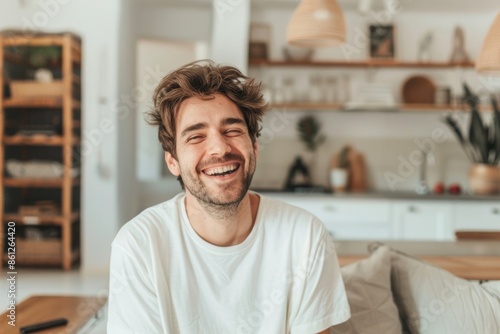 Portrait of a smiling man in his 30s laughing in front of crisp minimalistic living room