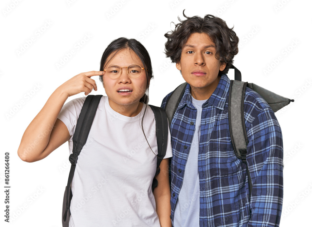 Young interracial student couple studying showing a disappointment gesture with forefinger. Young interracial student couple studying showing a disappointment gesture with forefinger.
