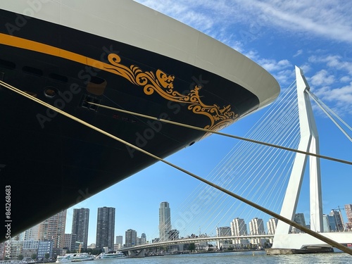 Bow of a ship moored in the city centre of Rotterdam, pointing at the Erasmus bridge showing the city skyline in the back photo