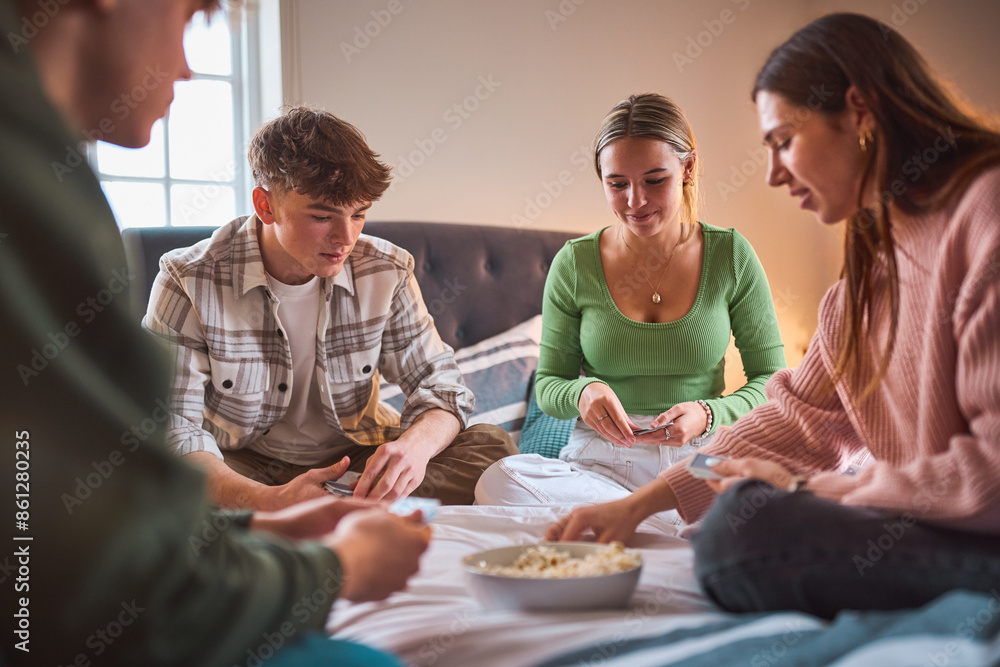 Group Of Teenage Girls And Boys At Home Hanging Out Laughing And Playing Cards In Bedroom Together Group Of Teenage Girls And Boys At Home Hanging Out Laughing And Playing Cards In Bedroom Together