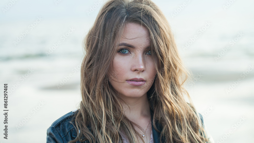 Attractive young adult woman with natural make-up and long wavy brown hair on blue sea beach outdoor portrait Attractive young adult woman with natural make-up and long wavy brown hair on blue sea beach outdoor portrait