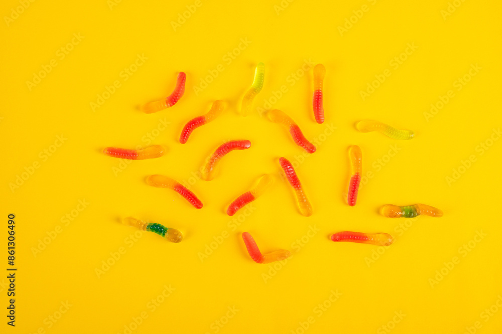 Fruit flavored worm shape, jelly candies. Isolated on yellow background. Fruit flavored worm shape, jelly candies. Isolated on yellow background.