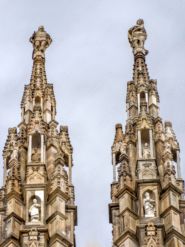 Statues on the roof of the Cathedral-Basilica of the Nativity of Saint Mary, the Duomo of Milano, under a cloudy sky. Travel to Italy. Statues on the roof of the Cathedral-Basilica of the Nativity of Saint Mary, the Duomo of Milano, under a cloudy sky. Travel to Italy.