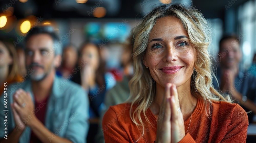 A joyful woman in an orange blouse claps her hands at a corporate event, surrounded by other smiling attendees, depicting a vibrant and engaging atmosphere. A joyful woman in an orange blouse claps her hands at a corporate event, surrounded by other smiling attendees, depicting a vibrant and engaging atmosphere.