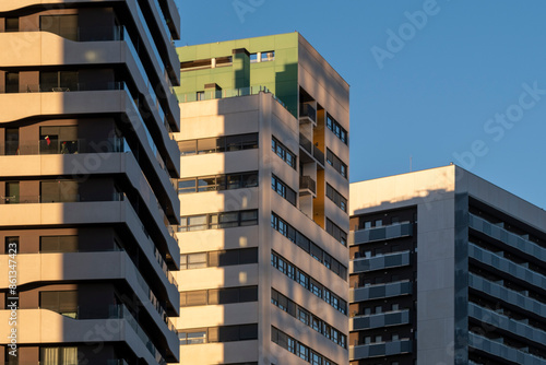 This image showcases modern high-rise buildings with geometric designs and contemporary architectural styles, bathed in warm light and set against a clear blue sky in Barcelona Spain photo