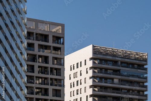 This image captures multiple apartment buildings standing tall against a clear blue sky, each showcasing different architectural designs and styles in an urban setting in Barcelona Spain