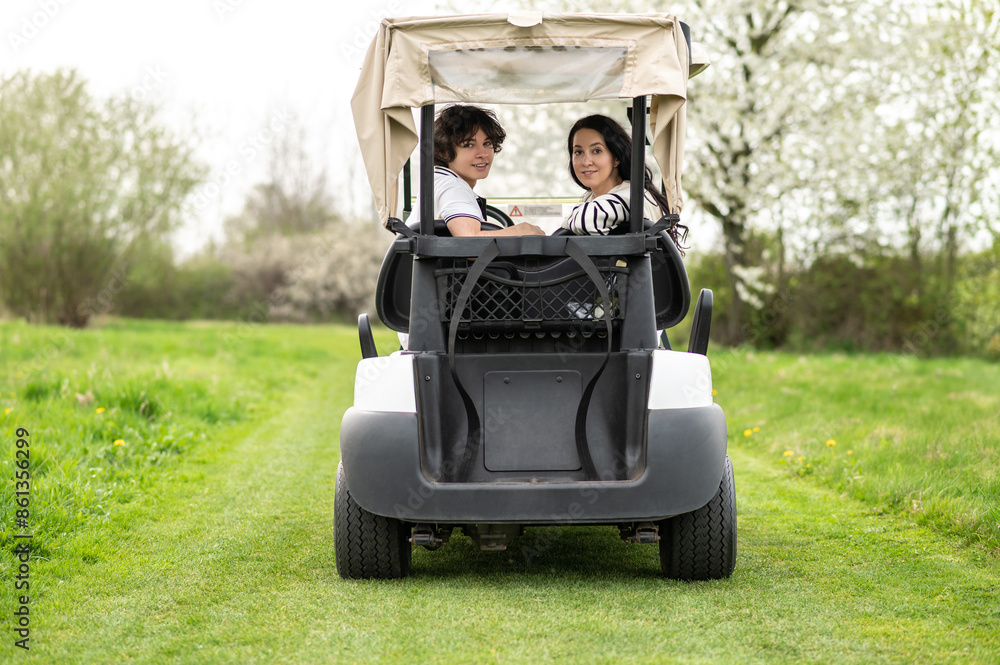 Fototapeta premium Young people driving a vehicle in a golf club and looking contented