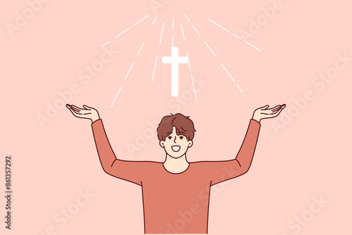 Man with christian cross above head rejoices at light coming from heaven and calls to visit church for prayers. Christian guy believes in miracle obtained by attending religious masses.