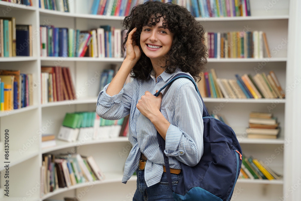 Cute woman in the library smiling nicely and looking contented