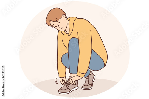 A little boy ties a shoelace on his shoe